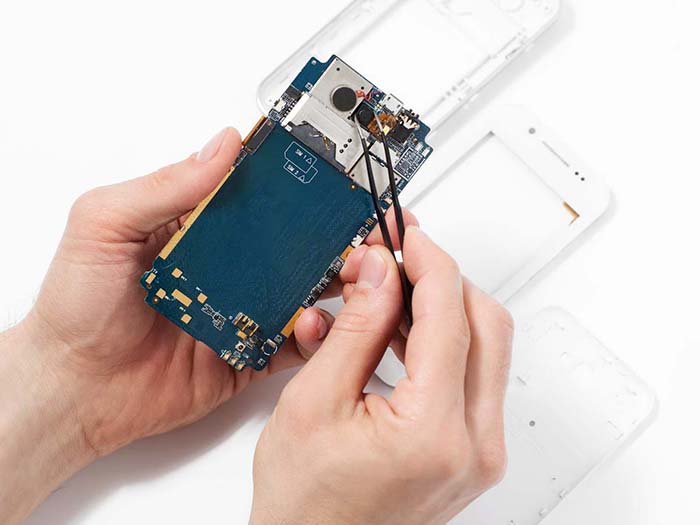 Repairman disassembling smartphone with tweezers. Unrecognizable repairer hands holding mobile phone circuit in electronics repair service, white background